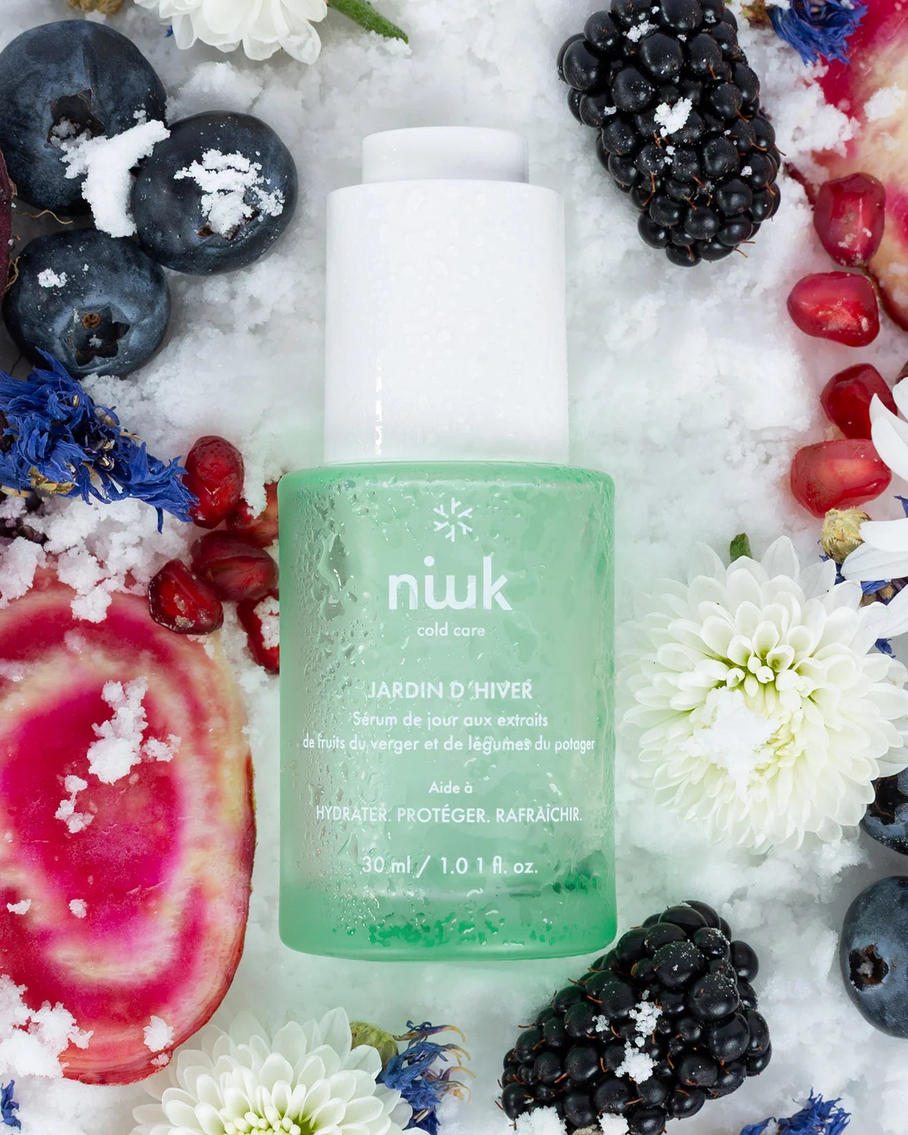 Green skincare bottle labeled 'niuk' surrounded by berries and flowers on a white background